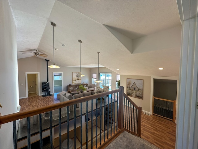 corridor with hardwood / wood-style flooring, a textured ceiling, and lofted ceiling