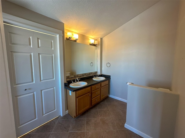 bathroom with a textured ceiling, tile patterned floors, and vanity