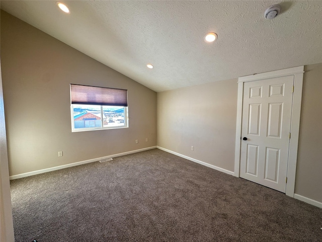 carpeted spare room with a textured ceiling and lofted ceiling