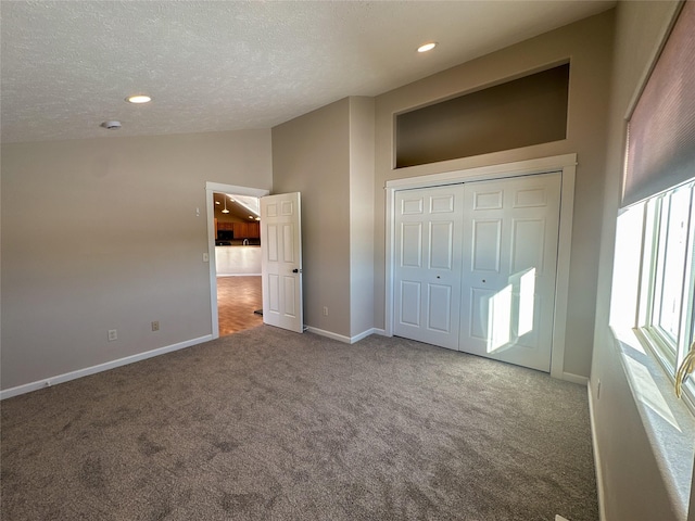 unfurnished bedroom featuring high vaulted ceiling, a textured ceiling, a closet, and carpet flooring