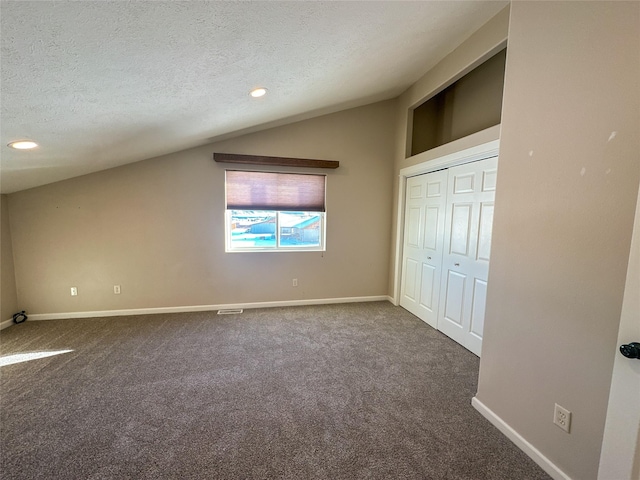 unfurnished bedroom with carpet flooring, a textured ceiling, a closet, and lofted ceiling