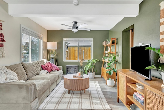 living room featuring light hardwood / wood-style flooring, beamed ceiling, and ceiling fan