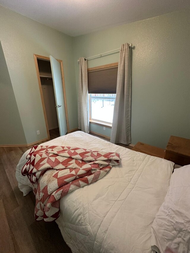 bedroom featuring wood-type flooring, a textured ceiling, and vaulted ceiling