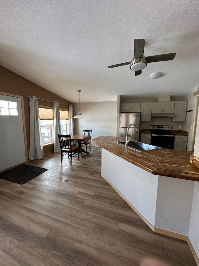 kitchen featuring electric stove, stainless steel fridge, gray cabinetry, hanging light fixtures, and wood counters