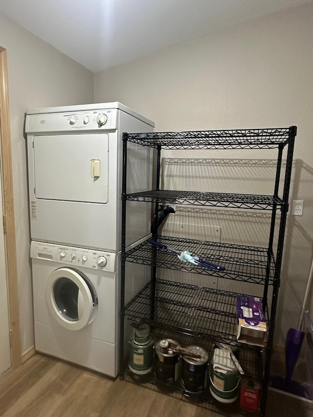 laundry room with stacked washer and dryer and hardwood / wood-style flooring