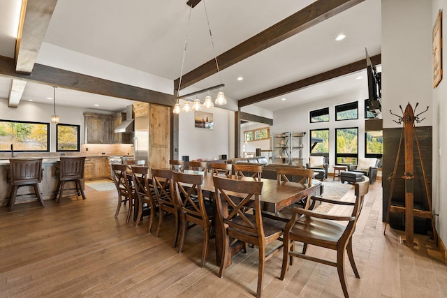 dining area featuring light hardwood / wood-style floors, beam ceiling, and a wealth of natural light