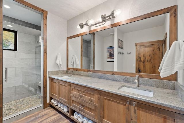 bathroom with wood-type flooring, a shower with door, and vanity