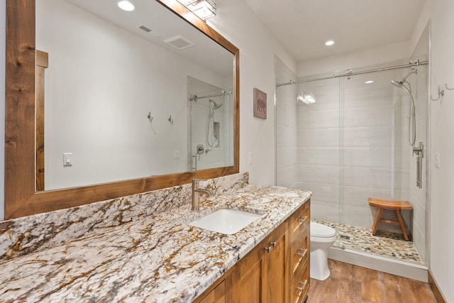 bathroom featuring vanity, hardwood / wood-style flooring, an enclosed shower, and toilet