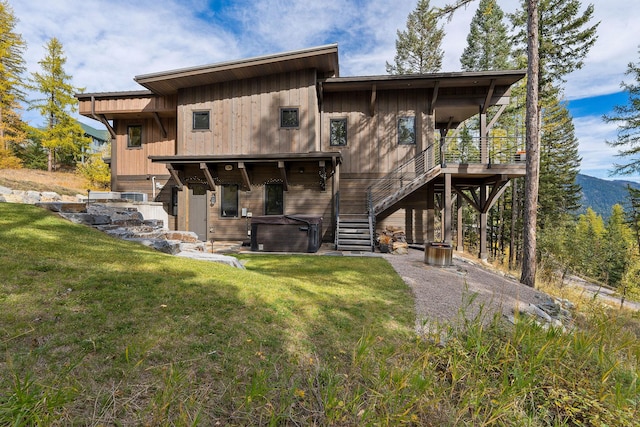 rear view of property with a lawn and a hot tub