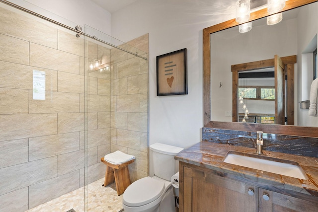 bathroom with toilet, vanity, and a tile shower