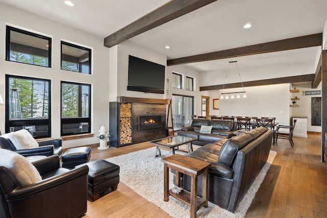 living room with light hardwood / wood-style flooring, beamed ceiling, and a premium fireplace