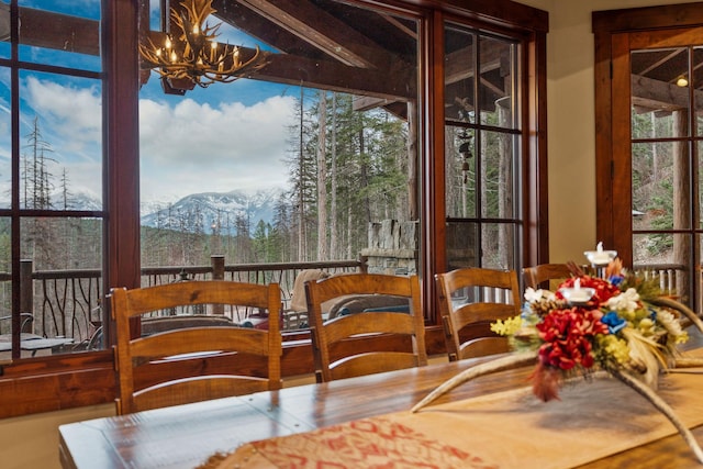 sunroom with a mountain view, an inviting chandelier, and plenty of natural light