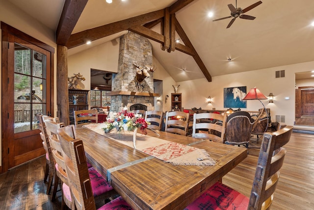 dining space featuring ceiling fan, a fireplace, hardwood / wood-style floors, high vaulted ceiling, and beamed ceiling