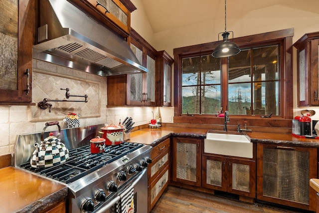 kitchen featuring hanging light fixtures, wall chimney exhaust hood, sink, decorative backsplash, and gas stove