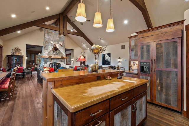 kitchen featuring beamed ceiling, a fireplace, sink, dark hardwood / wood-style flooring, and butcher block countertops