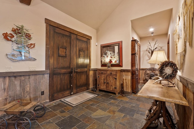 entrance foyer featuring wooden walls and lofted ceiling