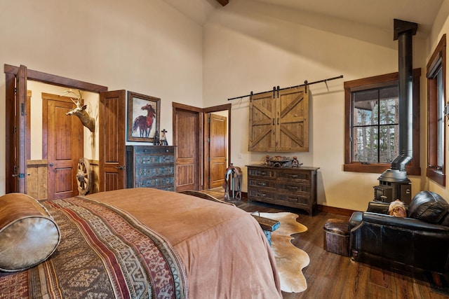 bedroom featuring a towering ceiling, dark hardwood / wood-style floors, and a barn door