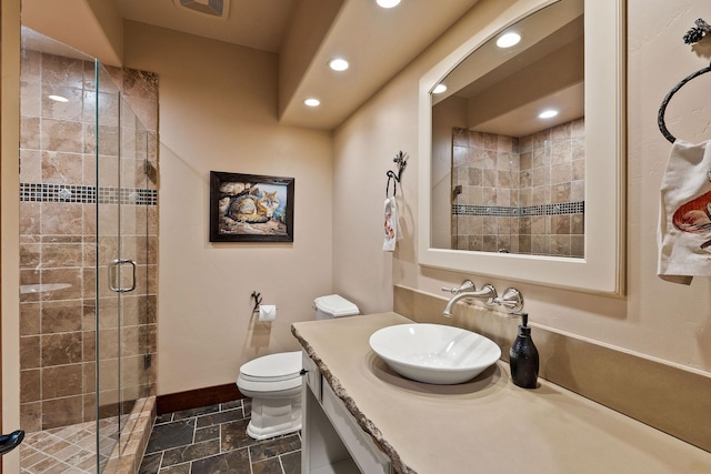 bathroom featuring a shower with door, toilet, and vanity