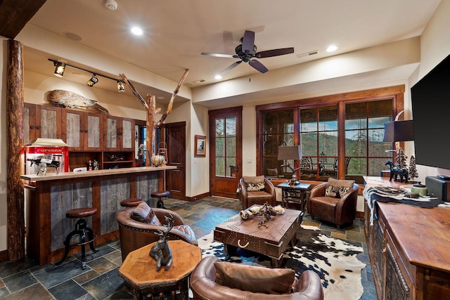 living room featuring ceiling fan and bar