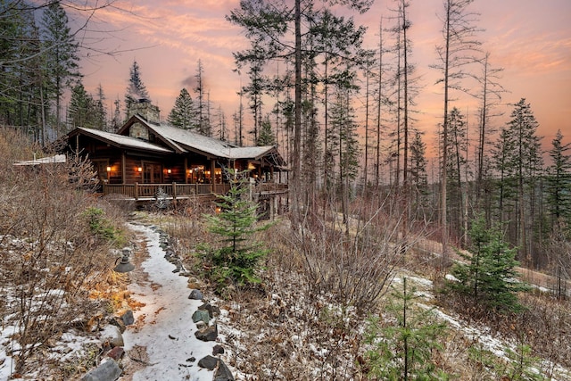 back house at dusk featuring a porch