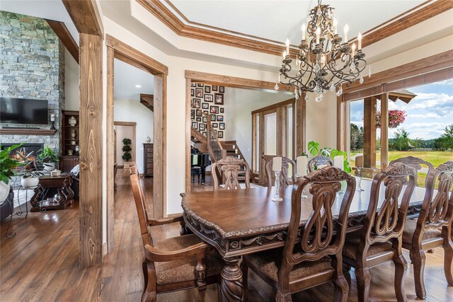 dining area with hardwood / wood-style flooring, a raised ceiling, a notable chandelier, and ornamental molding