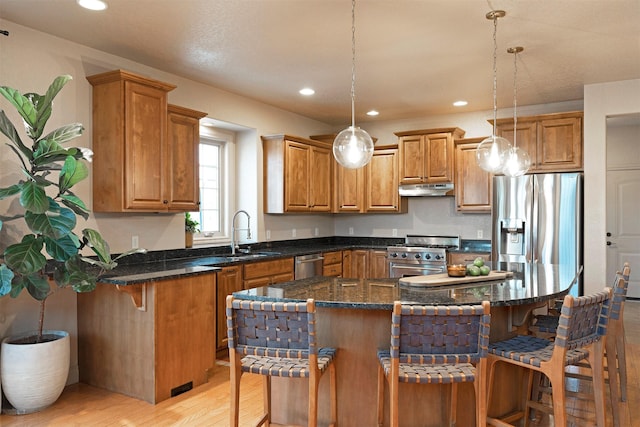 kitchen with decorative light fixtures, a breakfast bar, a center island, and stainless steel appliances