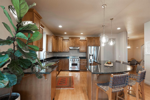 kitchen featuring decorative light fixtures, a kitchen island, light wood-type flooring, and stainless steel appliances