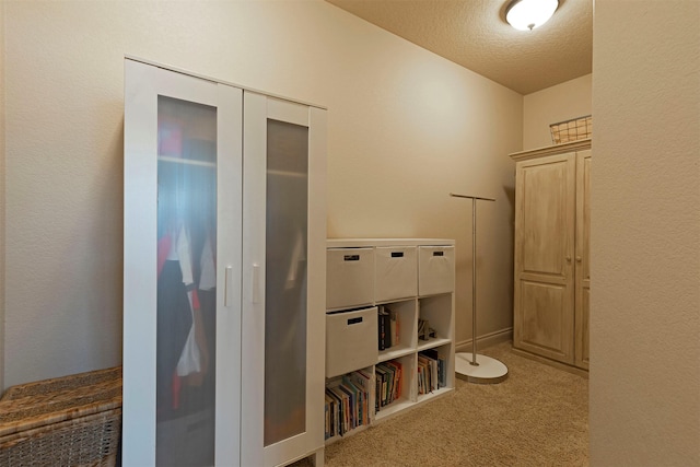 hallway with light colored carpet and a textured ceiling