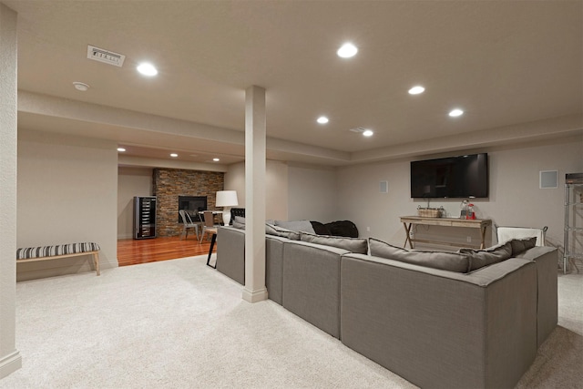 carpeted living room with a stone fireplace