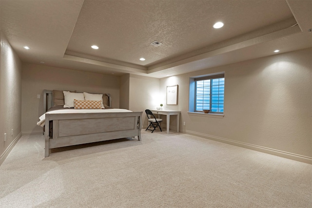 carpeted bedroom with a textured ceiling and a tray ceiling