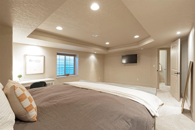 carpeted bedroom featuring a textured ceiling and a tray ceiling