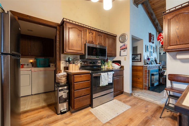 kitchen featuring brown cabinetry, independent washer and dryer, stainless steel appliances, light countertops, and light wood-style floors