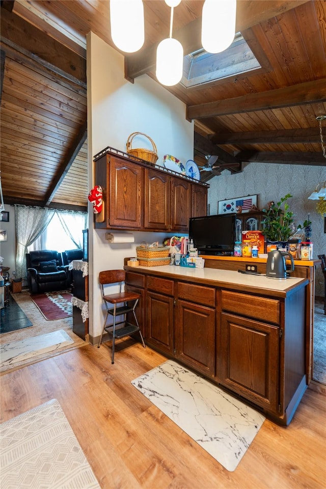 kitchen featuring pendant lighting, light countertops, lofted ceiling with beams, light wood-style floors, and wooden ceiling