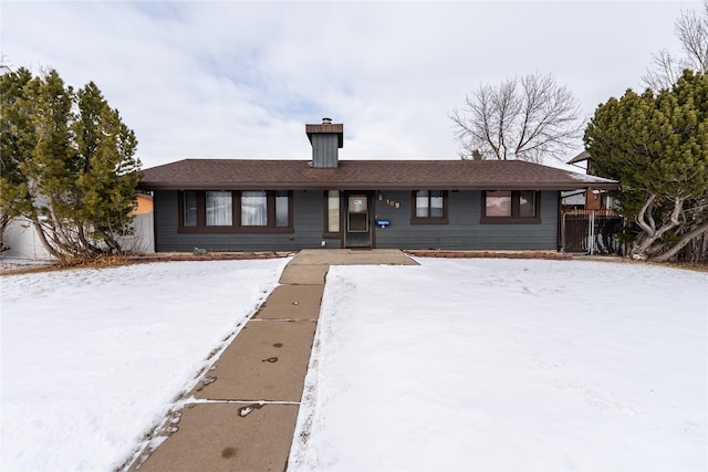 ranch-style home with a chimney and fence