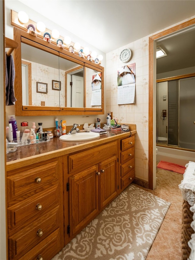 bathroom with vanity, enclosed tub / shower combo, and tile walls