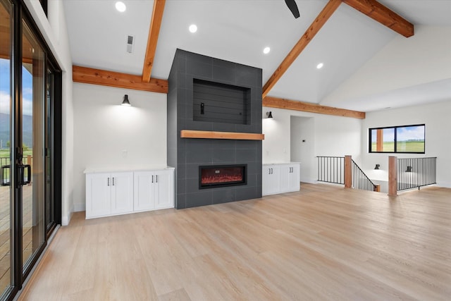 unfurnished living room featuring a fireplace, lofted ceiling with beams, and light hardwood / wood-style flooring