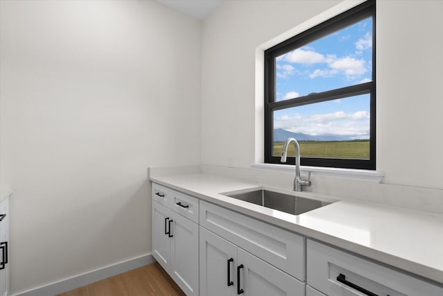 kitchen featuring white cabinetry, sink, and light hardwood / wood-style floors