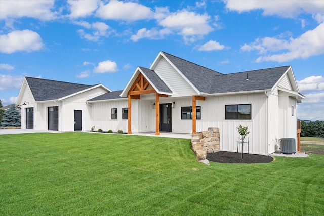 modern farmhouse style home featuring cooling unit, a garage, and a front lawn