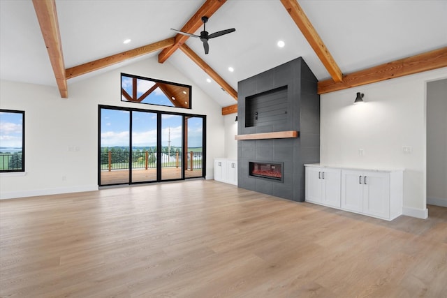 unfurnished living room with high vaulted ceiling, a fireplace, ceiling fan, light hardwood / wood-style floors, and beam ceiling