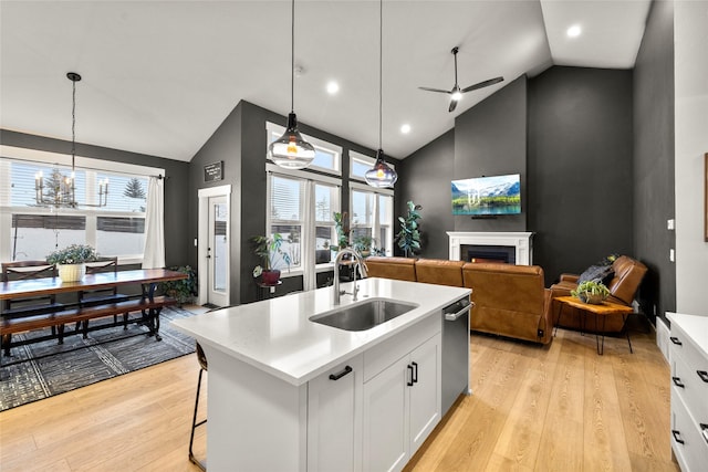 kitchen with pendant lighting, sink, white cabinetry, a center island with sink, and light wood-type flooring