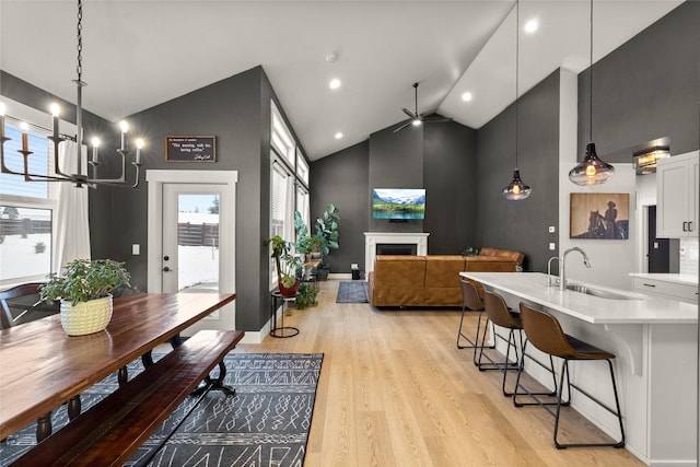 kitchen with pendant lighting, white cabinetry, sink, a breakfast bar area, and light hardwood / wood-style flooring