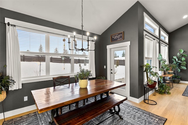 dining space with light hardwood / wood-style flooring, vaulted ceiling, and a chandelier