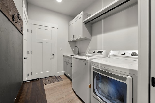 washroom featuring light hardwood / wood-style flooring, sink, washer and clothes dryer, and cabinets