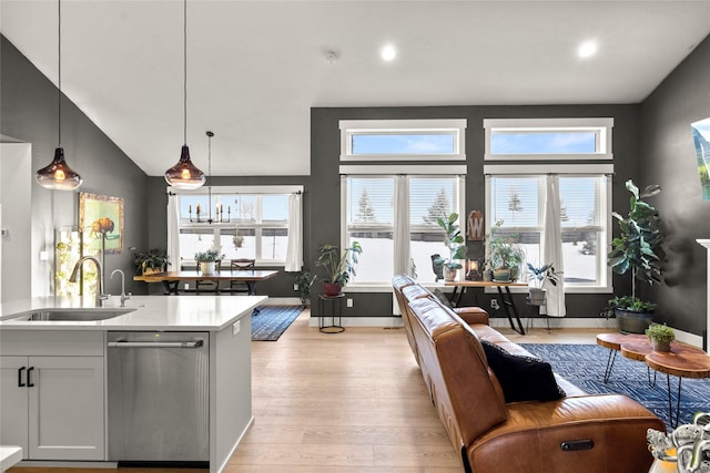 kitchen with dishwasher, white cabinetry, sink, hanging light fixtures, and light hardwood / wood-style flooring