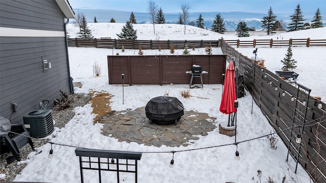 snowy yard featuring an outdoor fire pit, central AC unit, and a mountain view