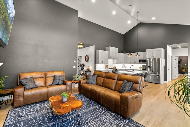 living room with sink, high vaulted ceiling, and light wood-type flooring