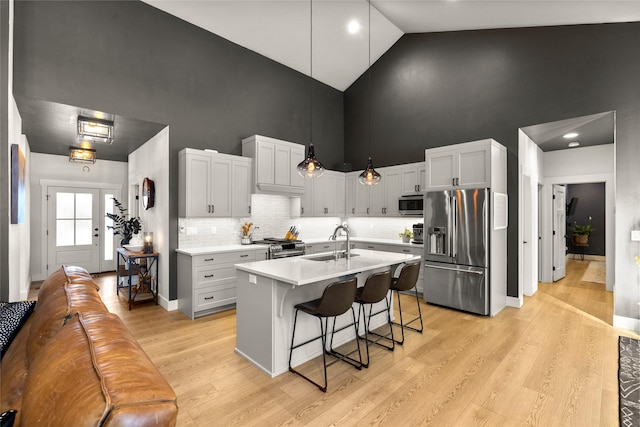 kitchen with a breakfast bar, high vaulted ceiling, an island with sink, sink, and high end appliances