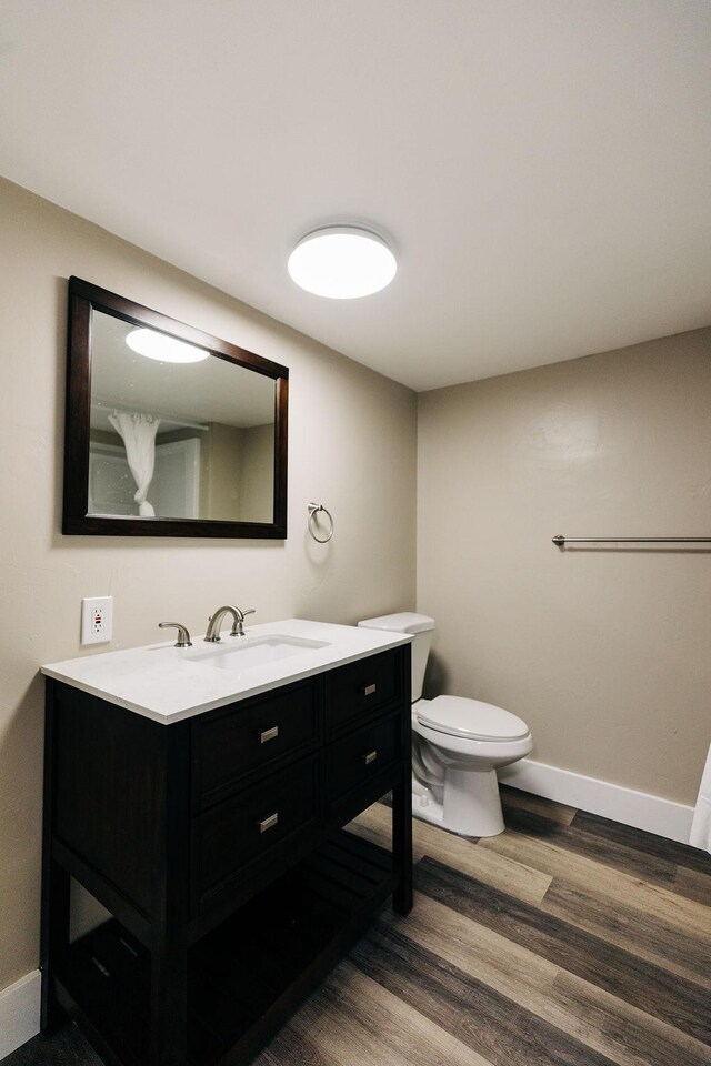 bathroom with wood-type flooring, toilet, and vanity