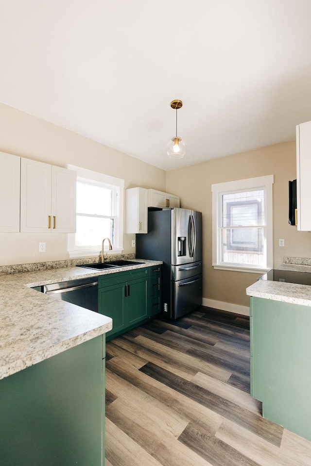 kitchen with appliances with stainless steel finishes, white cabinetry, sink, hanging light fixtures, and green cabinetry