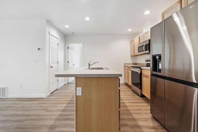 kitchen with appliances with stainless steel finishes, sink, a kitchen island with sink, and light hardwood / wood-style flooring